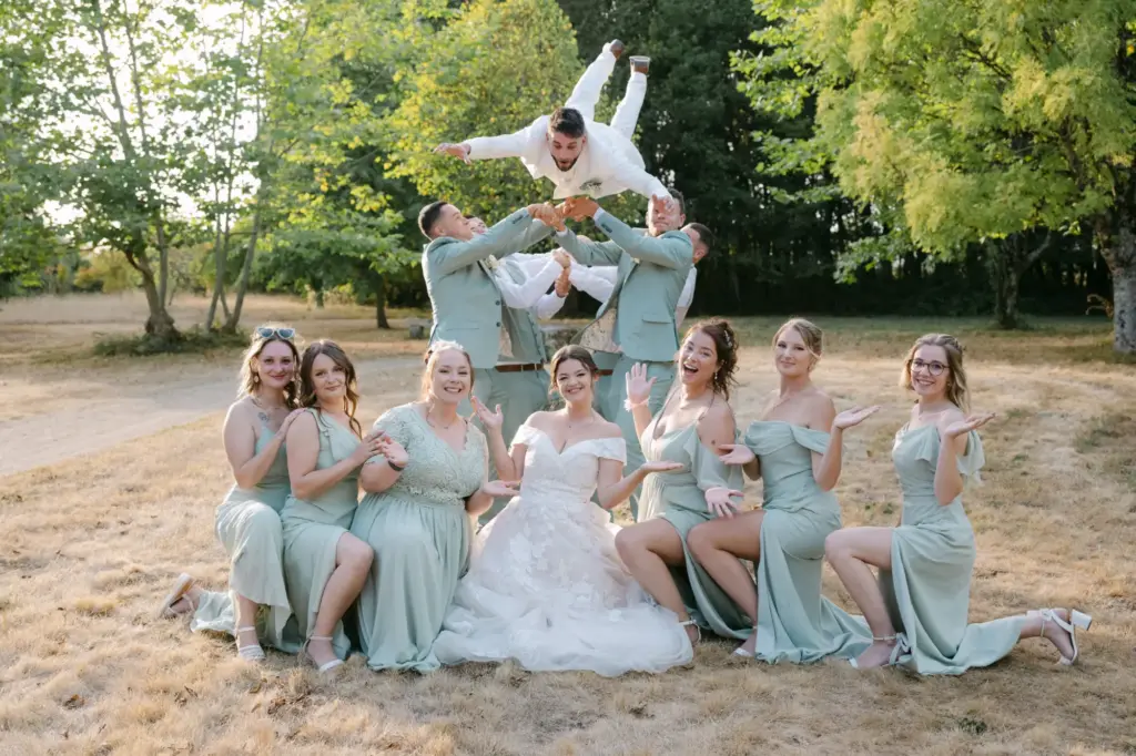 Photographie de mariage fun et dynamique, lancer du marié par les garçons d'honneur en extérieur, reportage de mariage convivial par Studio Timeless à Limoges.