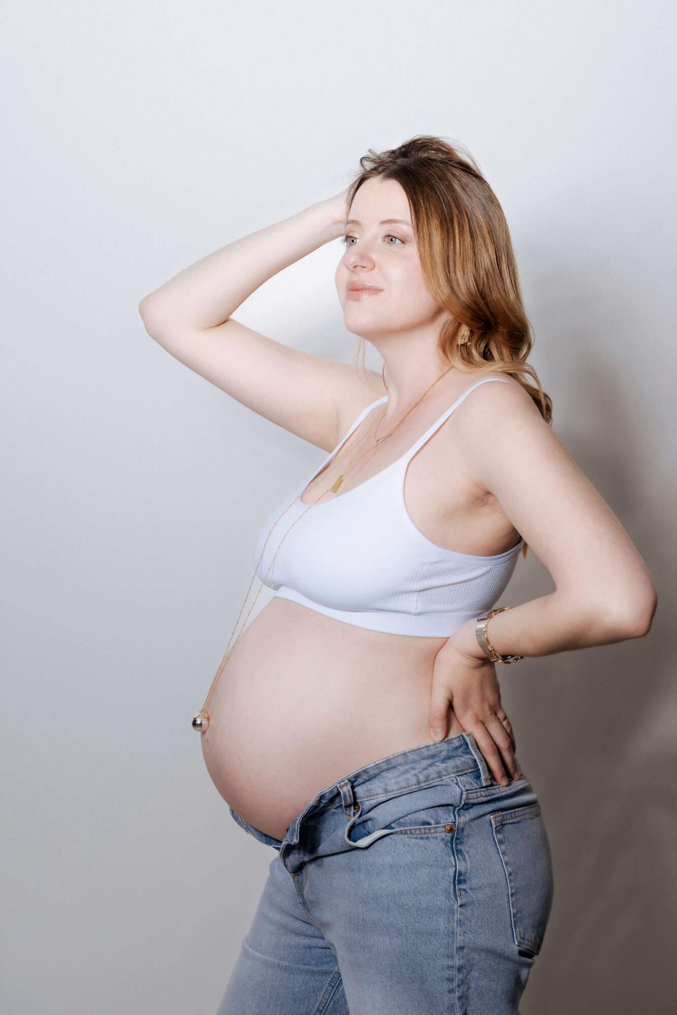 Femme enceinte brassière blanche et jean sur fond clair
