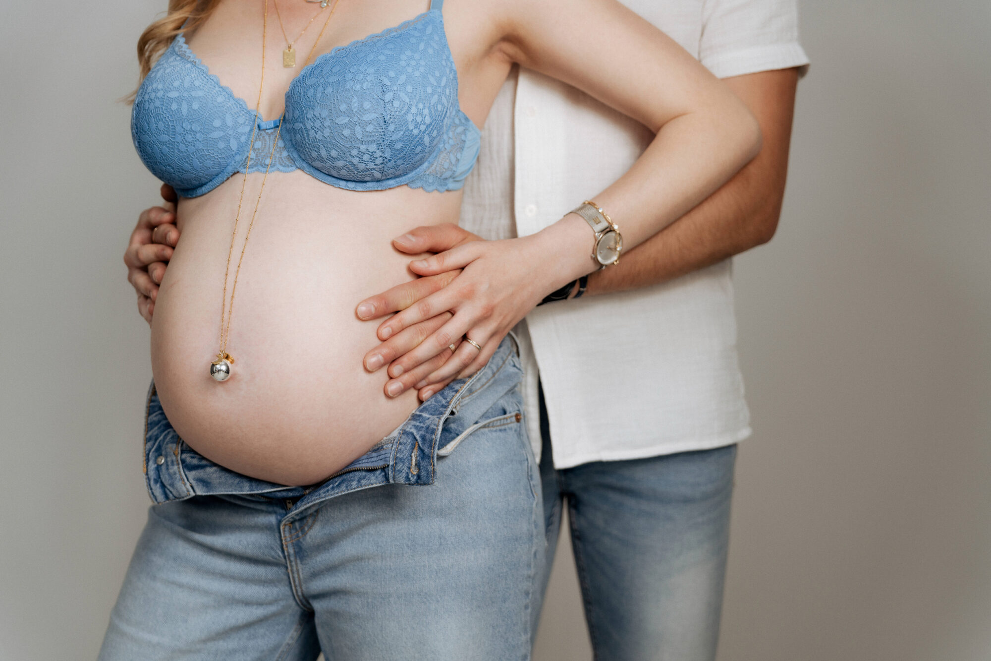 Gros plan mains couple sur ventre de grossesse fond clair