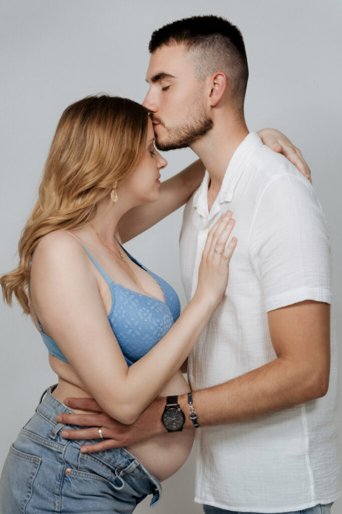 Couple tendresse baiser maternité, homme embrasse le front de sa femme enceinte, séance grossesse Limoges Studio Timeless