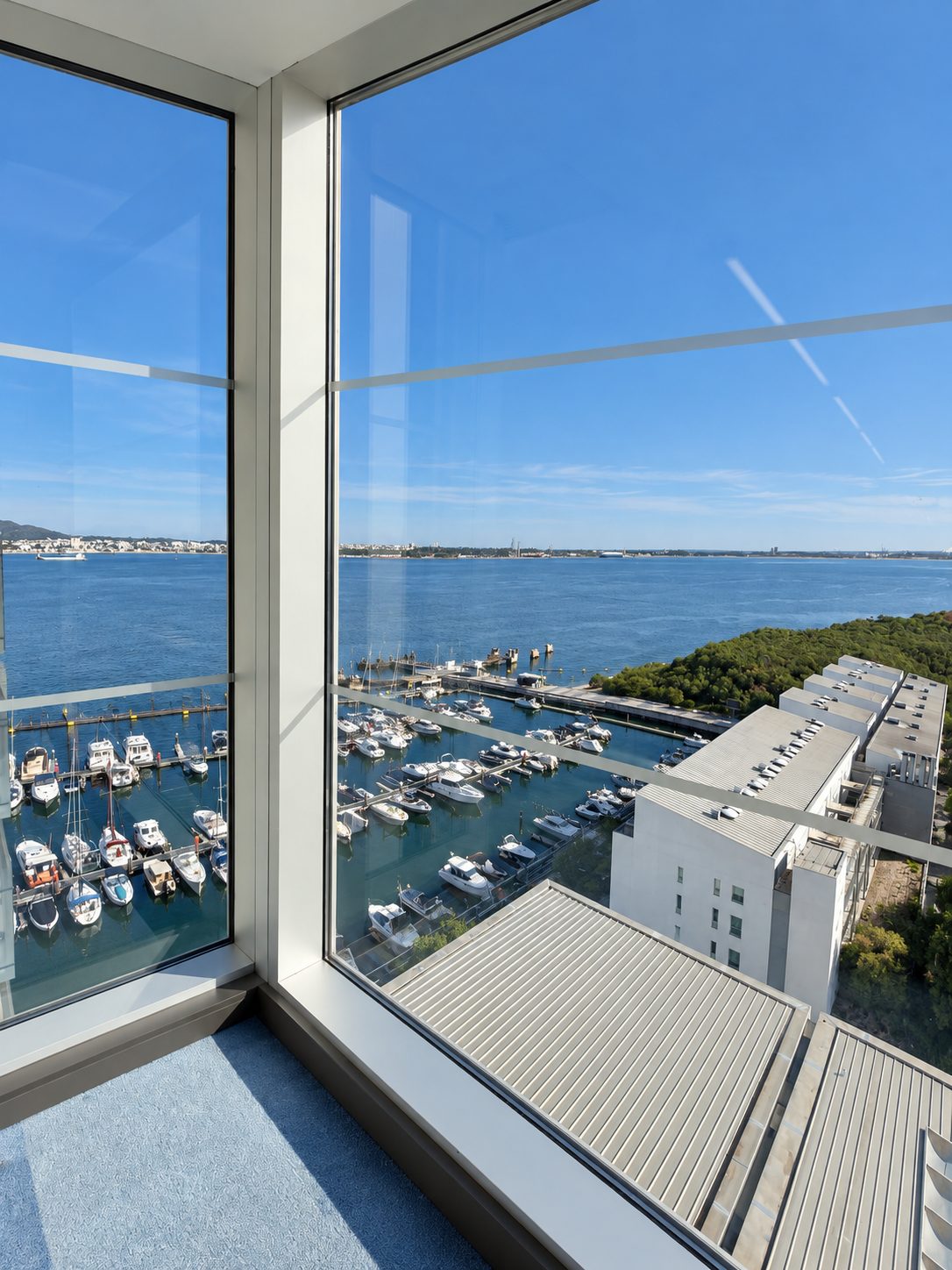 Vue sur une marina depuis la baie vitrée d’un hébergement